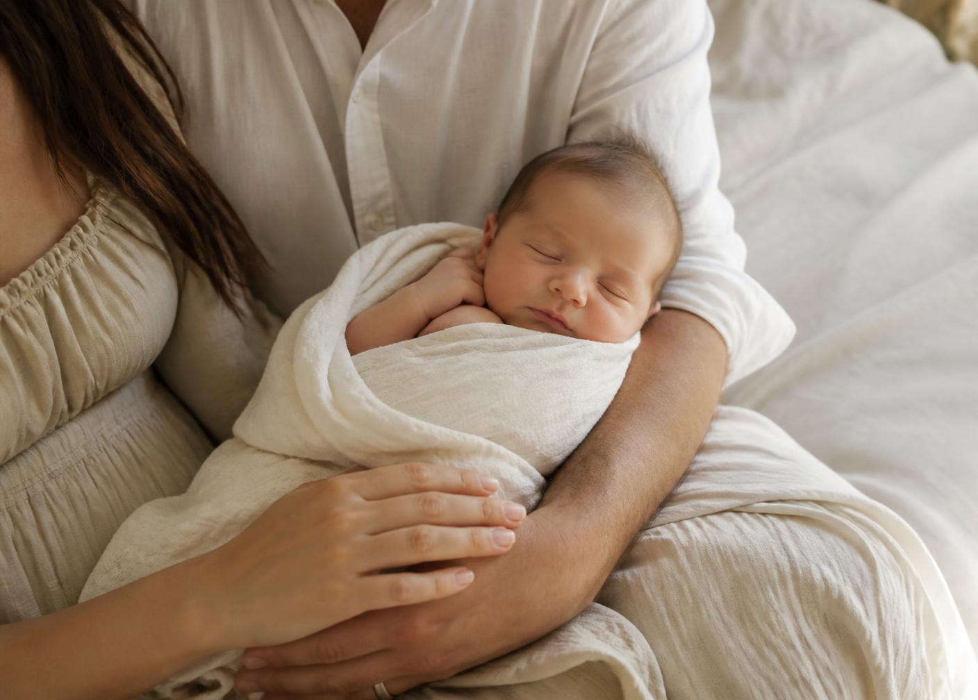 Newborn sleeping in a parent's arms during an in-home session